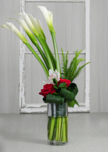 Bouquet "Élégance Passion" avec callas blancs, roses rouges et orchidées blanches, présenté en vase transparent.