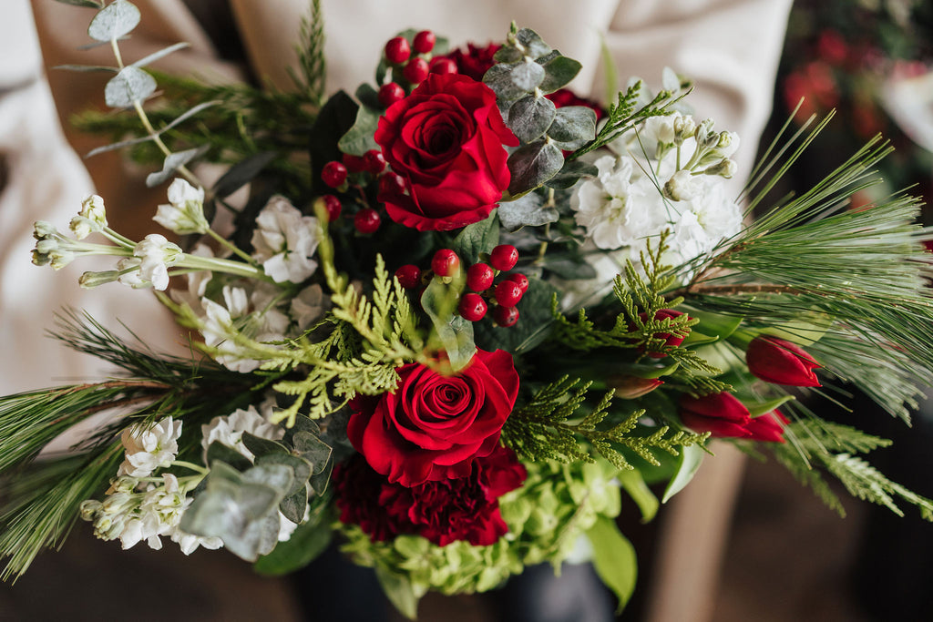 Bouquet festif rouge et vert avec roses rouges, eucalyptus et baies naturelles
