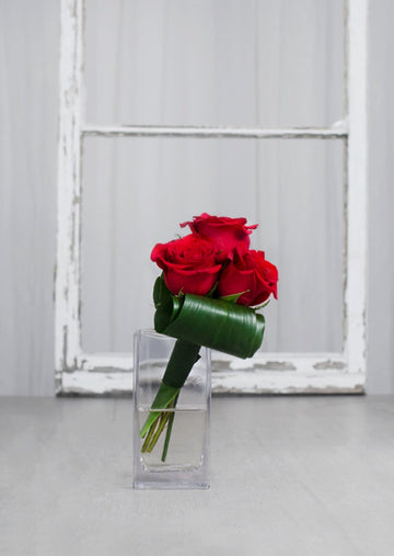 Bouquet "L'Amour à Trois Temps" avec 3 roses rouges dans un vase transparent, composition minimaliste et élégante.