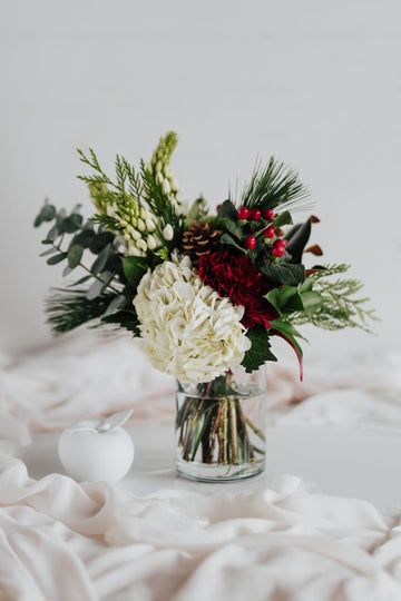 Bouquet nature festive avec hydrangées blanches, baies rouges, conifères et pommes de pin