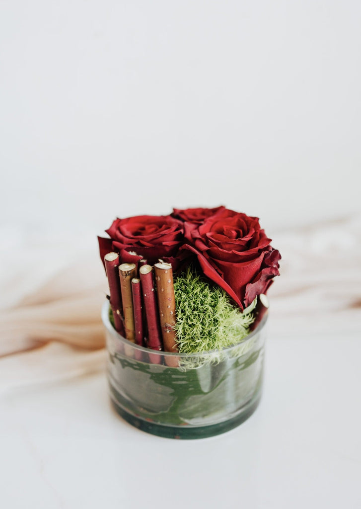 Bouquet "Tapis de Roses Rouges" présenté dans un vase bas, composé de roses rouges éclatantes et de feuillage vert, symbole d'élégance intemporelle.